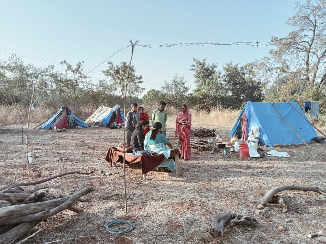 A roadside migrant labour camp of tarpaulin tents in dry open country